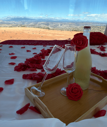 Cama con pétalos de flores y una botella de vino con vistas al desierto de Gorafe desde la Casa del Desierto de Cristal